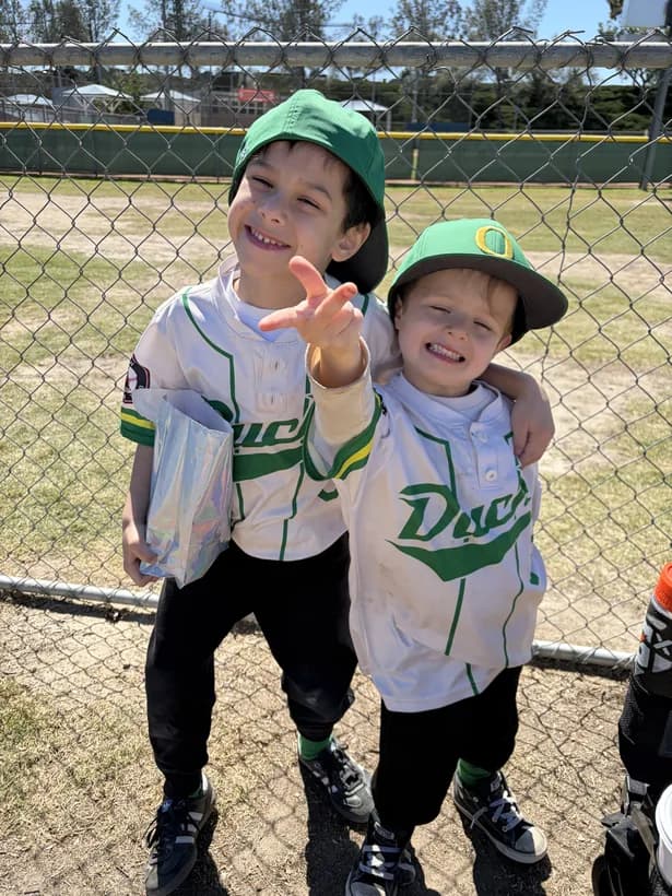 My two boys in their Ducks uniforms, arms around each other, one flashing a peace sign.